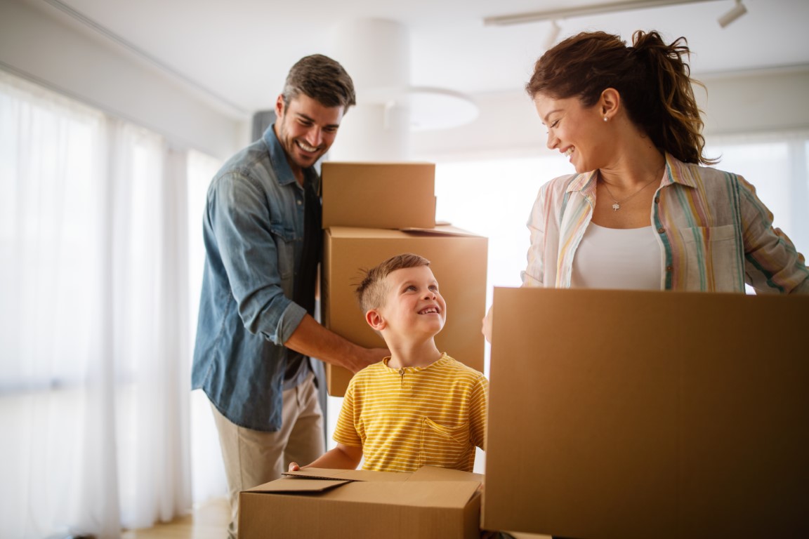 Happy family unpacking boxes in new home on moving day